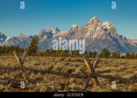 Der geteilte Gleiszaun verläuft über das davor ablaufende Salbeifeld Der Teton Berge im Grand Teton Nationalpark Stockfoto