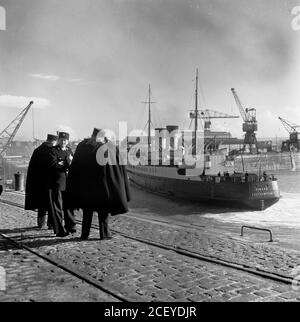 50er Jahre, historische, französische Gendarmen am Kopfsteinpflaster-Kai in Calais, Frankreich als große Passagierfähre kommt Dinard, Southampton, in den Hafen. Das Dampfturbinenschiff TS Dinard wurde 1924 von William Denny & Bros aus Dunbarton für die Southern Railway Company, Southampton, England, UK für die Strecke Southampton - St. Malo gebaut. Nach dem Krieg wurde sie als Auto- und Passagierfähre umgebaut und zwischen Dover und Boulogne eingesetzt. Zu dieser Zeit wurden noch Autos auf Schiffe mit Kran beladen. Sie blieb bis 1958 im Dienst. Stockfoto