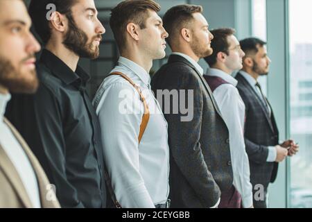 Seitenansicht auf junge kaukasische bärtige Geschäftsleute Blick Seite an Panoramafenster, jeder in stilvollen eleganten Anzug. Isoliert in modernen Büro Stockfoto