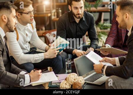 Business Coworking von jungen kaukasischen bärtigen Männern im Büro versammelten sich, um Geschäftsideen zu diskutieren, Erfahrungen und Meinungen auszutauschen, erfolgreiche Zusammenarbeit Stockfoto