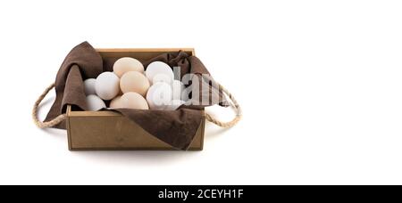 Hühnereier sind weiß und braun in einer schönen Holzverpackung mit einer braunen Leinenserviette. Stockfoto