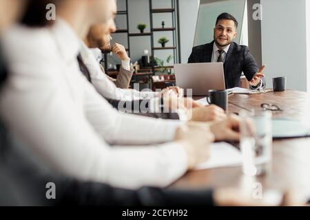 Business Coach, Führer Mann Rede zu Kollegen sitzen am Tisch im Büro. Angenehme bärtige Mann in Smoking stehen, die sein Projekt im Modus Stockfoto