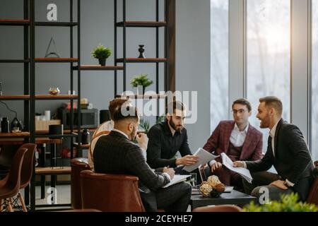 Business Coworking von jungen kaukasischen bärtigen Männern im Büro versammelten sich, um Geschäftsideen zu diskutieren, Erfahrungen und Meinungen auszutauschen, erfolgreiche Zusammenarbeit Stockfoto