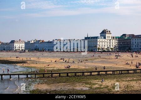 Llandudno, viktorianische Hotels an der South Parade und der gemischte Kiesel- und Sandstrand mit einem Steg am belebten Sommerabend. Stockfoto