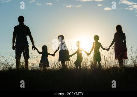Silhouette einer glücklichen großen Familie bei Sonnenuntergang. Stockfoto