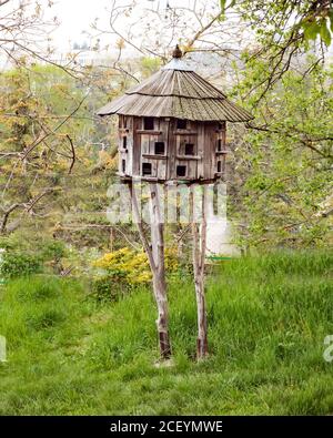Vintage handgemachtes Holzhaus für viele Vögel. Ungewöhnliches einzigartiges Rundvogelhaus auf hohen Ständen im Garten. Die Pflege von Wildtieren und Haustieren. Holzbalken Stockfoto