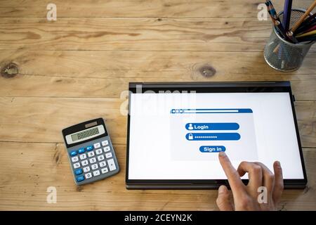 Online-Apps Hand drücken Anmelde-Taste auf dem Tablet Stockfoto