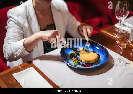 Tatented Koch brachte leckeres Dessert auf glorreichen ursprünglichen Teller, süße Kuchen mit verschiedenen Berris hübsch sieht lecker auf großen blauen Teller. Frau in Stockfoto