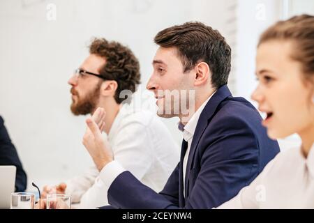 Geschäftstreffen von jungen kaukasischen Menschen, Probleme bei der Arbeit, müde von fluchen Kollegen, deprimiert und angre auf einander, isoliert in moder Stockfoto
