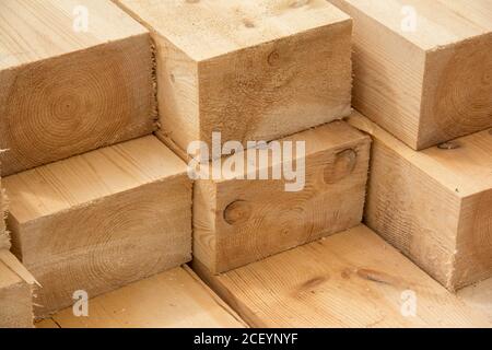 Stapel von hölzernen quadratischen Balken für den Bau. Material für den Bau eines Holzgebäudes. Große Holzbretter aus der Nähe Stockfoto