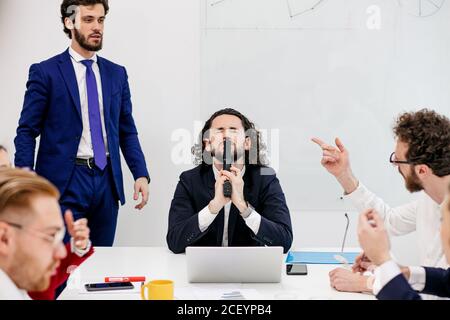 Gruppe von jungen kaukasischen Geschäftsleuten im Büro, junge Geschäftsmann suchen depressiv und besorgt über die Arbeit an einem Meetin, halten Waffe in den Händen, Stockfoto