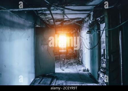 Dunkler Korridor in blauer Farbe und hell am Ende. Mysteriöser Tunnel in einem alten verlassenen Gebäude. Horror-Atmosphäre. Stockfoto