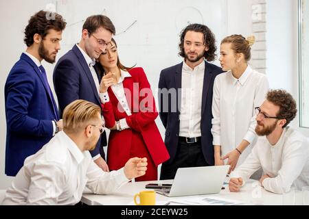 Freundliche Geschäftsleute arbeiten in modernen Büros zusammen, arbeiten gerne zusammen, nutzen Laptops und haben erfolgreiche nützliche Gespräche, Diskussionen Stockfoto