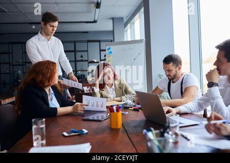 Junge Geschäftsleute traurig mit Ergebnis ihrer Arbeit, enttäuscht rothaarige Frau sitzen in der Mitte des Tisches Stockfoto