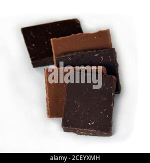 Milch- und dunkle Schokoladenwürfel. Schokoladenstapel auf weißem Hintergrund. Stapel Schokolade. Kleine dunkle Schokoladenstücke. Stockfoto