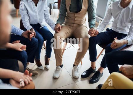 Viele Mitarbeiter versammelten sich, um für die beste Arbeit im Büro zu beten, erfolgreiche Business-Team sitzen im Kreis Stockfoto