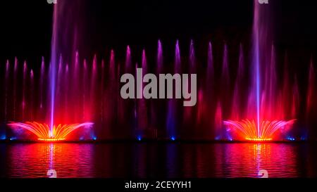 Nacht Laser-Brunnen zeigen, auf dem Ufer des Roshen, der ukrainischen Stadt Winniza.Musikbrunnen mit Laser-Animationen.Musikbrunnen Roshen in Winniza, Ukraine.Abendshow Roshen Brunnen. Stockfoto