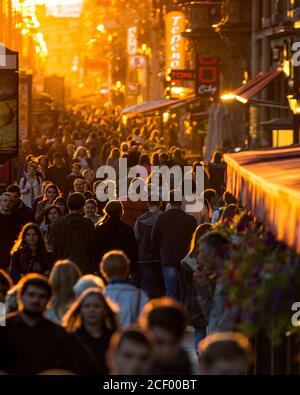 Menschenmenge auf einer Fußgängerzone während der Hauptverkehrszeit am Abend bei Sonnenuntergang. Stockfoto