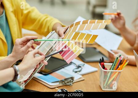 Foto von weiblichen Hand halten Farbe Pallete, Hände mit Bleistiften zeigen auf notwendige Ton, Menschen, die Entscheidung Konzept Stockfoto