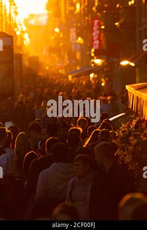 Menschenmenge auf einer Fußgängerzone während der Hauptverkehrszeit am Abend bei Sonnenuntergang. Stockfoto