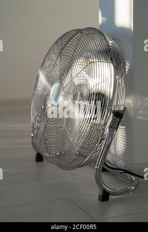 Silberner Ventilator aus Metall auf Holzboden zu Hause Stockfoto