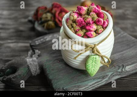 Blume Tee Rose Knospen in einer weißen Vase auf einem alten Holztisch. Nahaufnahme Stockfoto