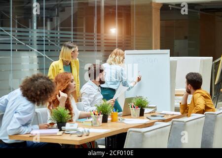 Ruhige unabgelenkt Frau schreibt Business-Plan an Whiteboard, will ernsthafte Kollegen beeindrucken, helle junge Mitarbeiter in interessanten informieren konzentriert Stockfoto