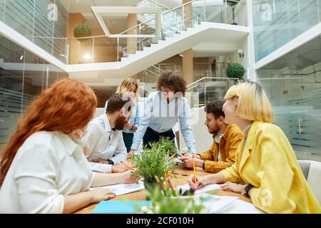 Junge kreative Team von talentierten Menschen lösen Arbeitsprobleme im modernen Büro, arbeiten hart in guter Stimmung nicht auf Kamera, horizontale Aufnahme Stockfoto
