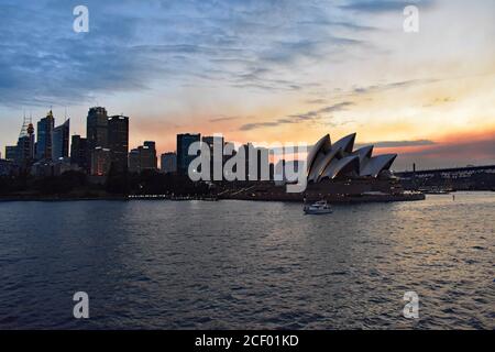 Sydney Opera House und das City Centre CBD bei einem dramatischen Sonnenuntergang vom Wasser des Sydney Harbour aus. New South Wales, Australien. Stockfoto