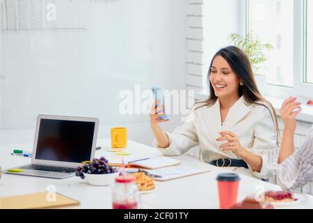 Positive junge kaukasische Lachen über lustige Witz reden auf Handy bei der Arbeitspause, fröhliche Corporate Mitglied des Teams, Büroangestellte. Laptop und c Stockfoto