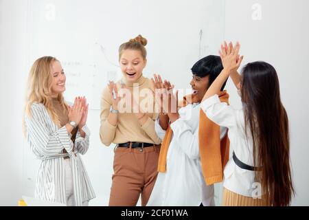 Überraschte Frauen in Freizeitkleidung im Büro zusammen, in Schock mit geöffnetem Mund. Feiern Sie ihren Sieg in Business-Projekt, gute Arbeit der vielfältigen weiblichen Stockfoto