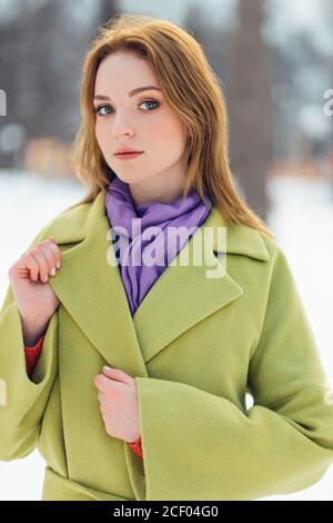 Porträt von gut aussehende kurzhaarige Frau in grünen Maxi-Mantel gekleidet steht im Winter verschneiten Straße. Glamouröse attraktive junge Dame Modell in luxuriös Stockfoto