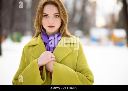 Atemberaubende kurzhaarige schöne Frau trägt grünen Maxi Mantel steht im Winter verschneiten Straße. Glamouröse attraktive junge Dame Modell in luxuriösen outerw Stockfoto