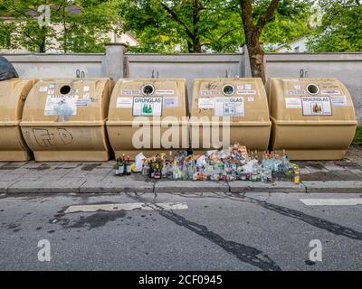 Leere Flaschen stehen vor überfüllten Behältern in einer Stadt. Ein Symbol für die tatsächlichen Abfallprobleme in der Welt. Stockfoto