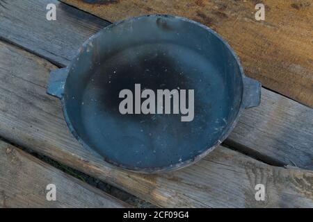 Alte geräucherte gusseiserne Bratpfanne auf einem Holztisch Hintergrund Nahaufnahme. Stockfoto