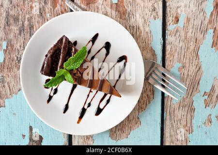 Scheibe Schokoladenkäsekuchen auf dem Teller, oben Blick über einem rustikalen blauen Holzhintergrund Stockfoto