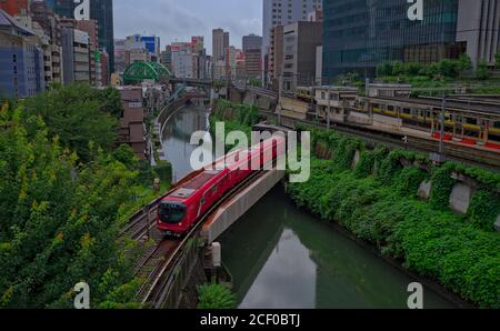 Bunkyo, Tokio / Japan - Juli 26 2020: Ein leuchtend roter Zug nach Ikebukuro fährt über den Kanda-Fluss in der Nähe des Bahnhofs Ochanomizu im Zentrum von Tokio auf einer Stockfoto