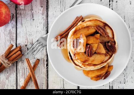 Herbst Pfannkuchen Stapel mit gebackenen Äpfeln, Pekannüsse und Zimt gekrönt mit Ahornsirup, Blick von oben Stockfoto