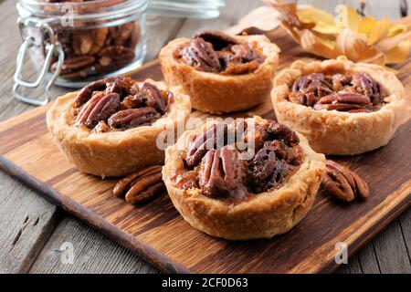 Mini Pekannüsse Torten, Nahaufnahme Szene auf einem hölzernen Server vor einem rustikalen Holz Hintergrund Stockfoto
