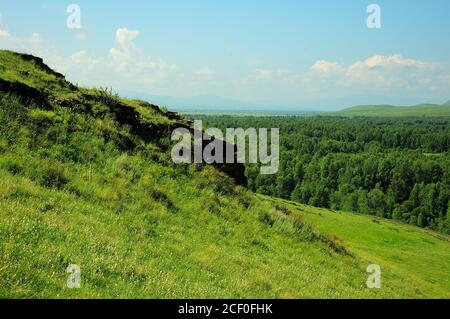 Eine alte Mauer, die entlang der Spitze eines hohen grasbewachsenen Hügel mit Blick auf ein malerisches Tal verläuft. Bergkette Truhen, Chakassien, Südsibirien, Russi Stockfoto