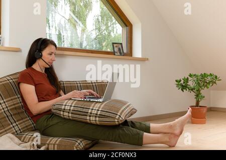 Frauen, die von zu Hause aus an einer Telefonkonferenz arbeiten. Schreibtisch aus Kissen. Neues normales Konzept Stockfoto