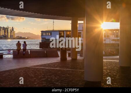 Frauen sitzen neben Star Ferry Pier, Tsim Sha Tsui, Kowloon, Hongkong Stockfoto