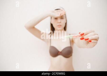 Portrait junge Frau mit Windpocken im Bett liegen und messen Temperatur Stockfoto