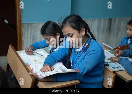 Jodhpur, Rajasthan, Indien - 10. Januar 2020: Indische Schülerinnen studieren im Klassenzimmer Prüfung nehmen / Test Schreiben in Notebooks. Bildung Stockfoto