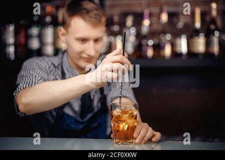 Barkeeper schüttelt Cocktail mit Eis in Glas langen Löffel Stockfoto