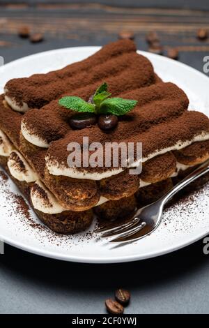 Klassisches Tiramisu Dessert auf Keramikplatte auf Holzhintergrund Stockfoto