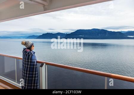 Alaska Kreuzfahrt Reise Luxus Urlaub Frau beobachten Innenpassage landschaftlich Kreuzfahrt Tag auf Balkon Terrasse mit Blick auf die Berge und Naturlandschaft Stockfoto