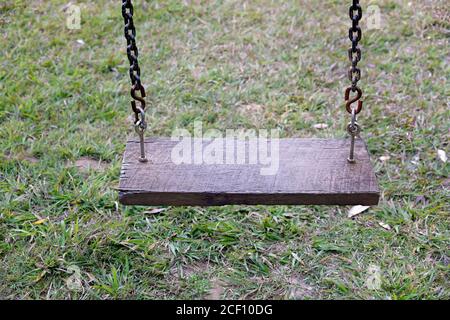 Nahaufnahme einer Kinderschaukel mit Holzsitz und Kette Stockfoto