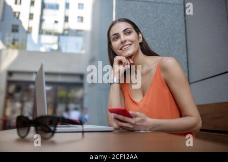 Dunkelhaarige hübsche Frau mit einem Smartphone erwartet Stockfoto