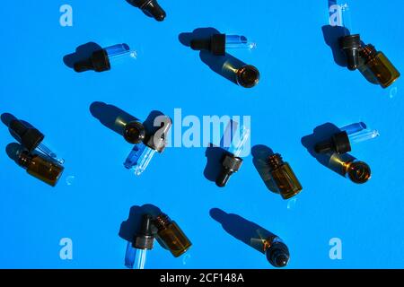 Flaschen ätherischer Öle auf farbigem Hintergrund, flach liegend. Kosmetische Produkte. Dropper. Stockfoto